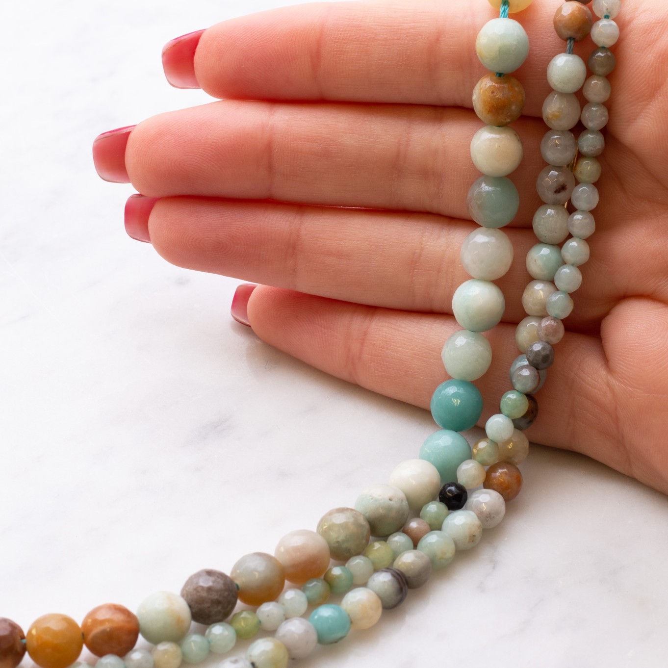 sot1788-multi-coloured-faceted-amazonite-round-beads-kernowcraft-hand.jpg